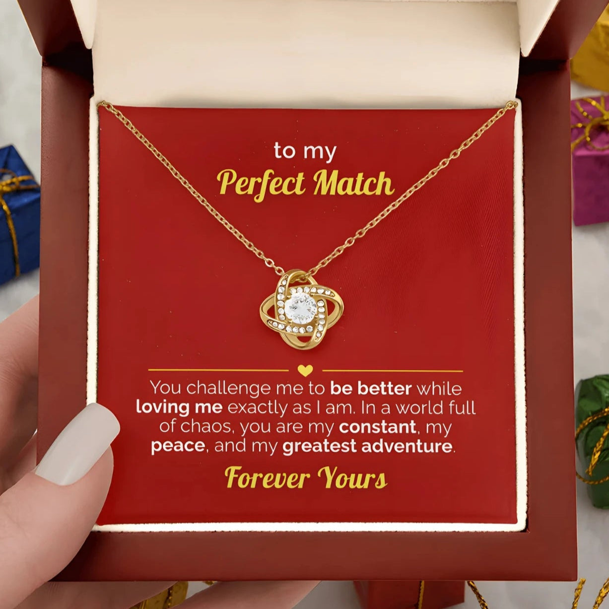 Gold necklace in a gift box with a romantic message, held by a hand.